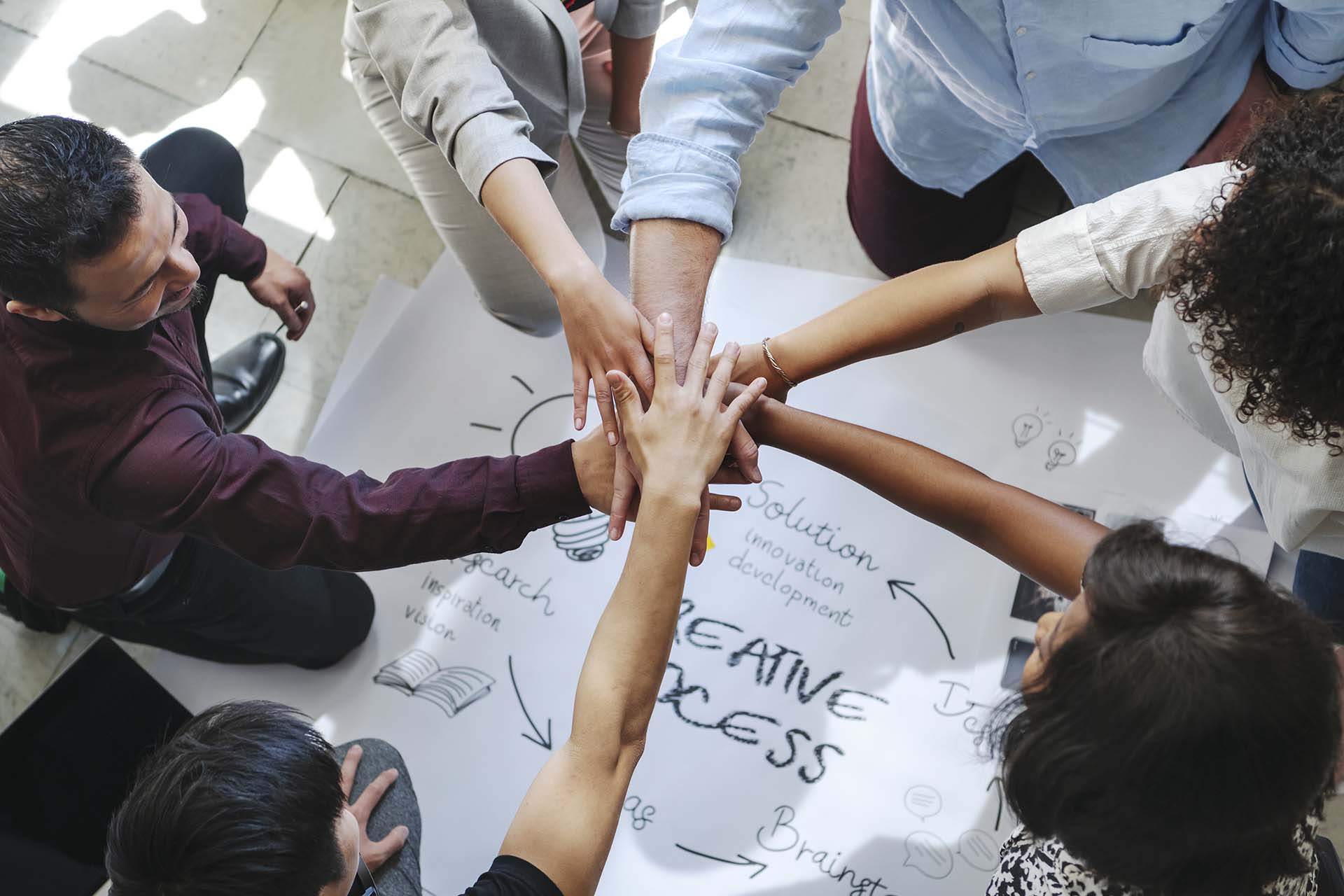 Happy team putting their hands together for success